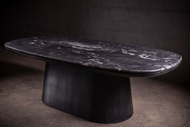 Table de salle à manger - Une étude en contraste — le plateau en quartzite cuiré offre une profondeur tactile qui change avec la lumière, ancré par un mat noir...